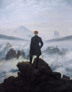 Un randonneur se tient comme une figure de dos au centre de la composition. Il observe une mer de brouillard presque impénétrable au milieu d'un paysage rocheux.