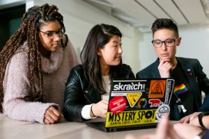 Photo of three people working together in front of a laptop