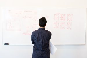 Man standing in front of white board with flowchart drawn on it.