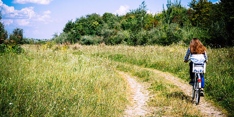 woman riding a bike through a field