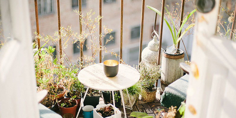 candle on a table on a balcony surrounded with plants