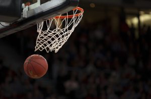 Basketball passing through a basketball net.