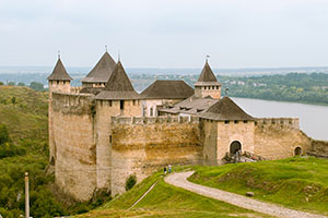 zoomed out view of an old castle. It is in the countryside next to a river.