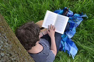 man leaning against a tree reading