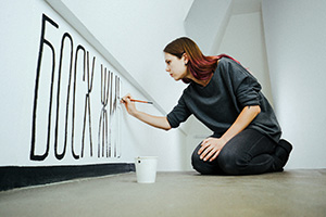 Young woman handpainting Ukrainian letters on a wall