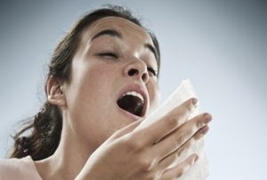 a woman sneezing into a tissue