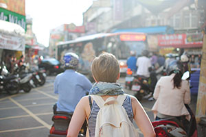 blonde woman with backpack in city with signs in Chinese