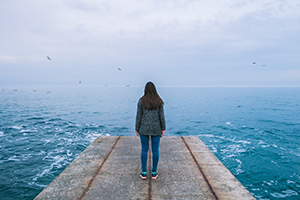 woman on dock looking out at the sea