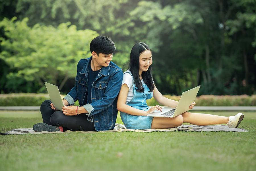 A male student sitting by a female student on the grass
