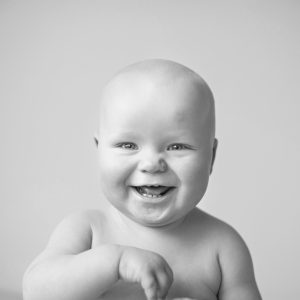 Black and white photo of bald baby boy laughing.