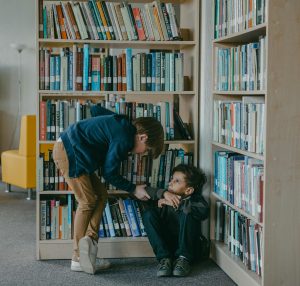 Bully leaning down into seated victim in library.