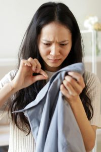 A woman finding a hair in a man's shirt.