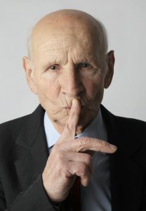 Old man with secret, finger to lips.